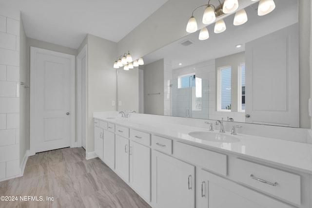 bathroom featuring a shower with shower door and vanity