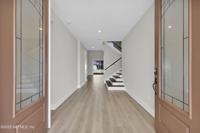 entrance foyer featuring light wood-type flooring, baseboards, and stairway