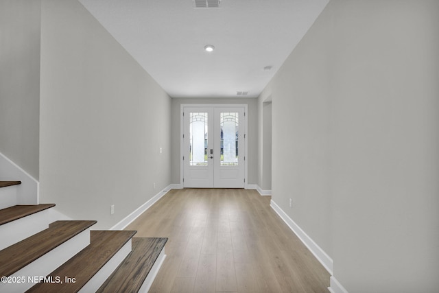 entryway featuring light wood finished floors, visible vents, baseboards, stairs, and french doors