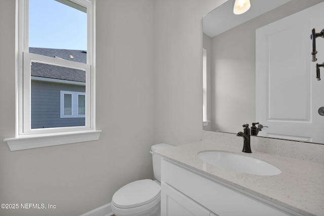 bathroom featuring baseboards, vanity, and toilet