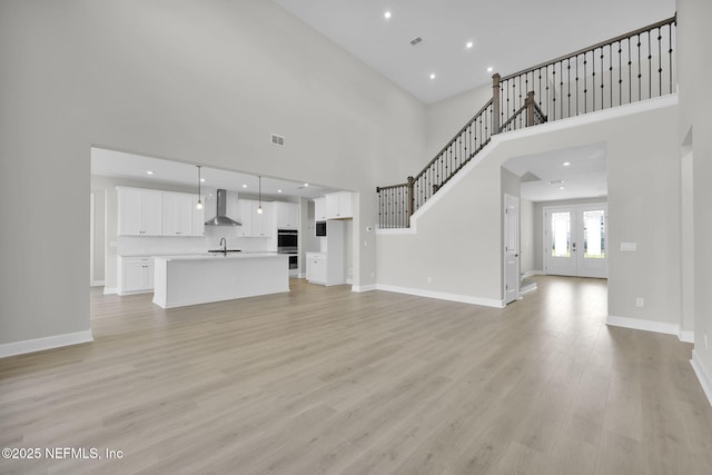 unfurnished living room featuring french doors, light wood finished floors, visible vents, and baseboards