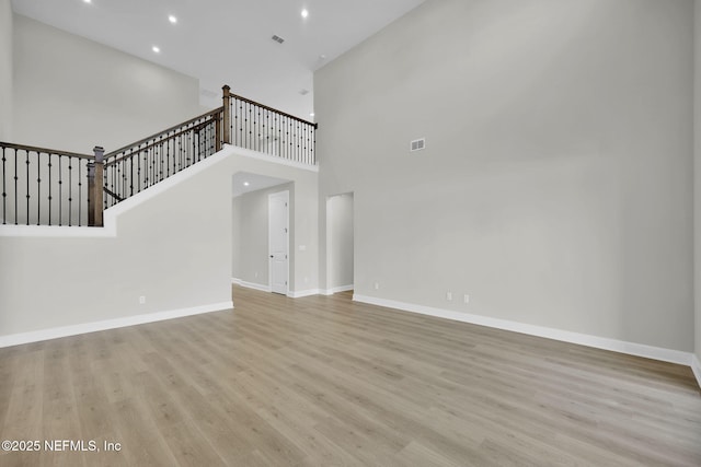 unfurnished living room featuring wood finished floors, visible vents, and baseboards