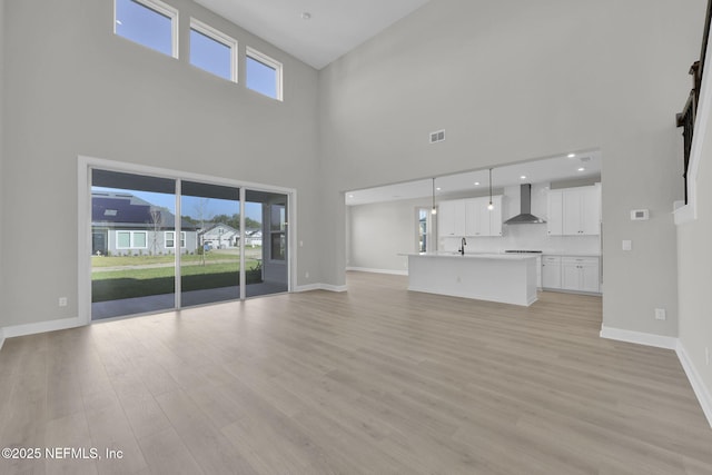 unfurnished living room featuring light wood-style flooring, baseboards, and a wealth of natural light