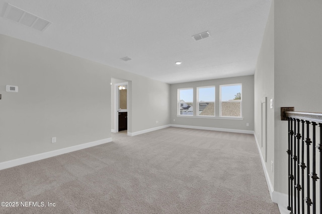 spare room featuring baseboards, visible vents, and light colored carpet