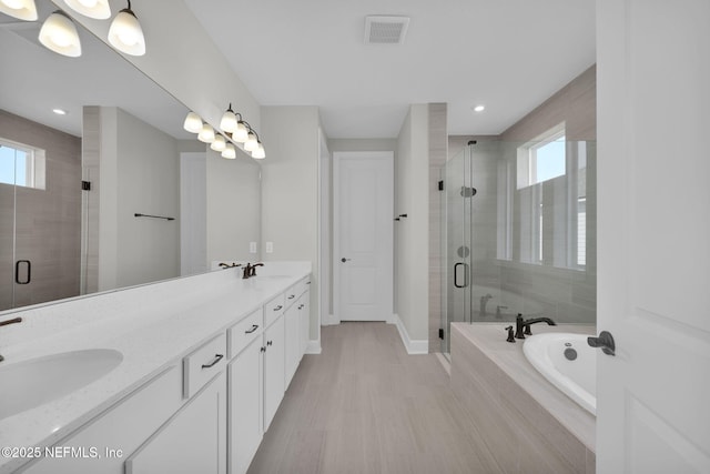 full bathroom featuring a stall shower, plenty of natural light, visible vents, and a sink