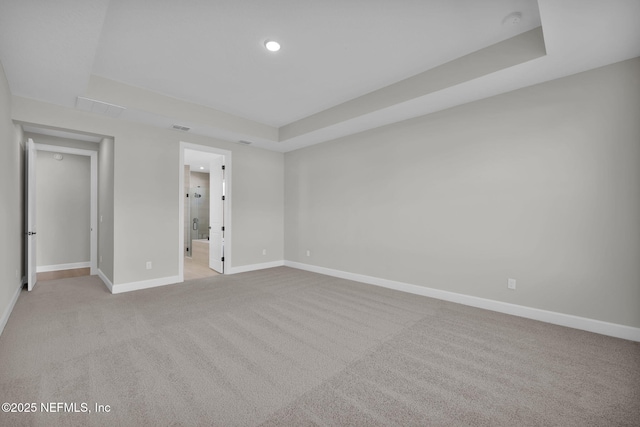 unfurnished bedroom featuring a tray ceiling, carpet flooring, visible vents, and baseboards