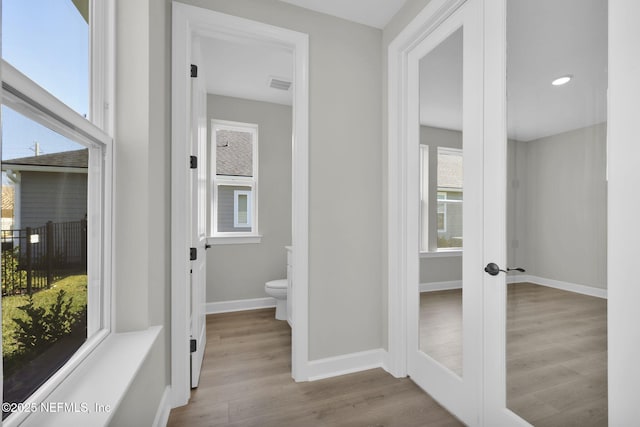 bathroom featuring french doors, visible vents, toilet, wood finished floors, and baseboards