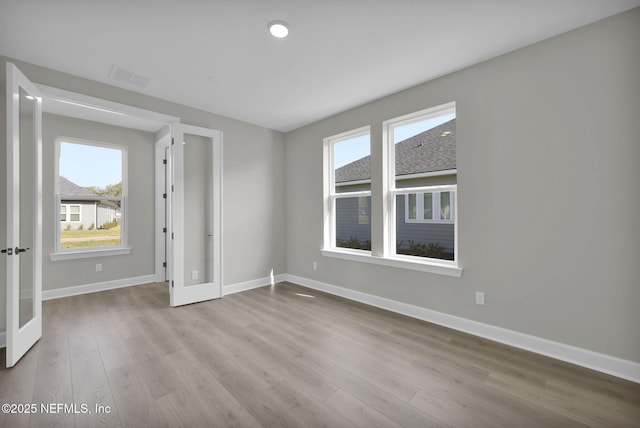 empty room featuring french doors, wood finished floors, visible vents, and baseboards