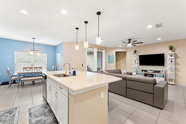 kitchen featuring white cabinets, hanging light fixtures, a center island with sink, and sink