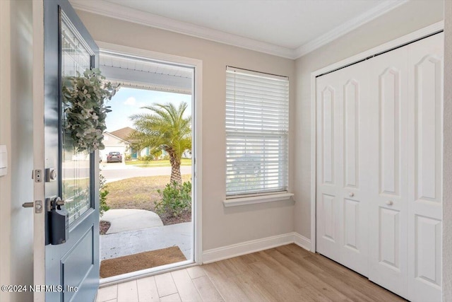 entryway with a wealth of natural light, light hardwood / wood-style floors, and crown molding