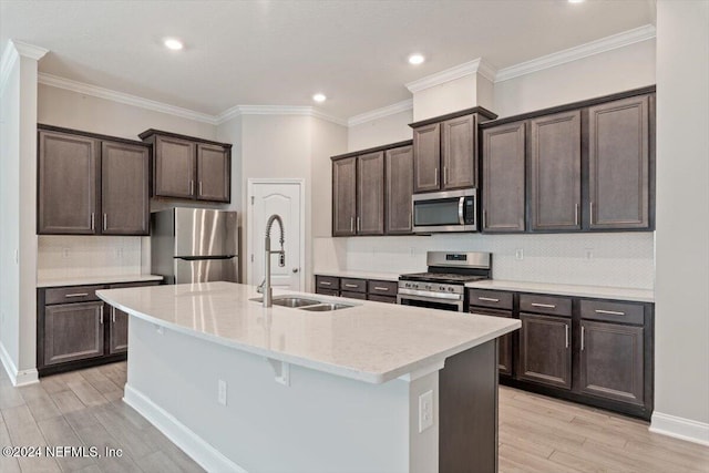 kitchen with light hardwood / wood-style floors, sink, a kitchen island with sink, crown molding, and appliances with stainless steel finishes