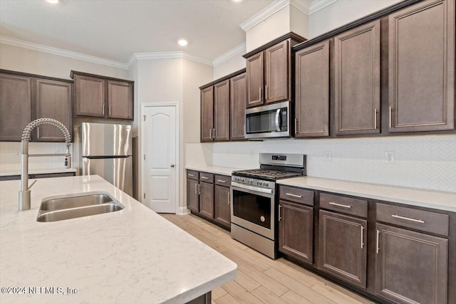 kitchen featuring crown molding, light wood-type flooring, appliances with stainless steel finishes, dark brown cabinetry, and sink