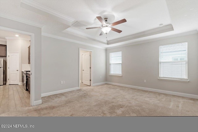 carpeted empty room featuring ceiling fan, a raised ceiling, and crown molding