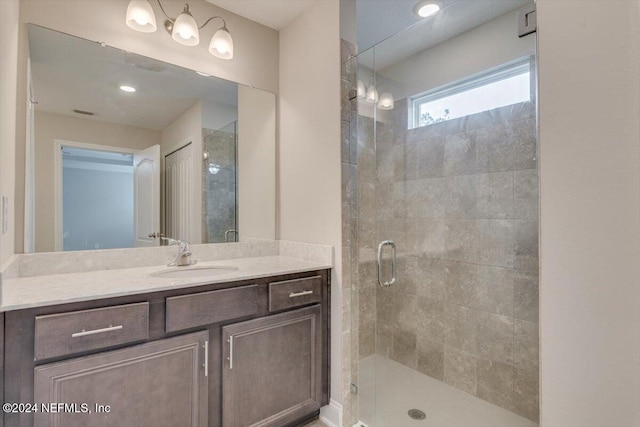 bathroom featuring a shower with shower door and vanity