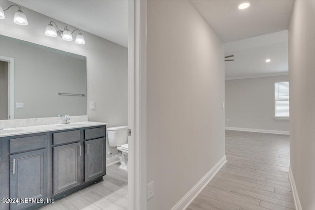 bathroom featuring ornamental molding, vanity, hardwood / wood-style flooring, and toilet