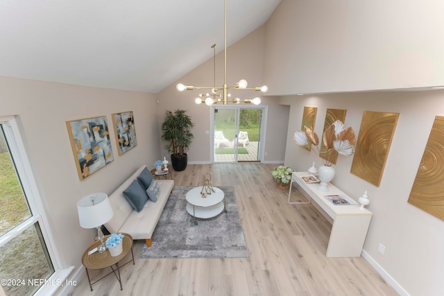 living room with high vaulted ceiling, a chandelier, and light hardwood / wood-style floors