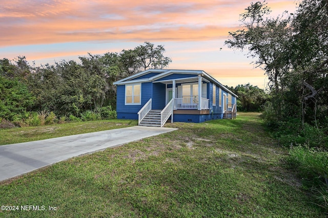 manufactured / mobile home featuring a lawn and covered porch