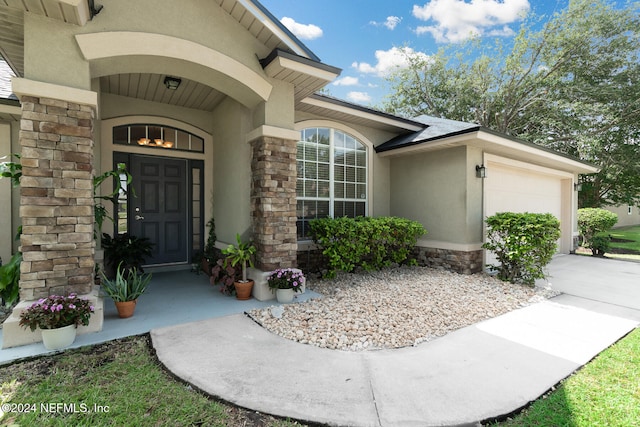 view of exterior entry featuring an AC wall unit and a garage