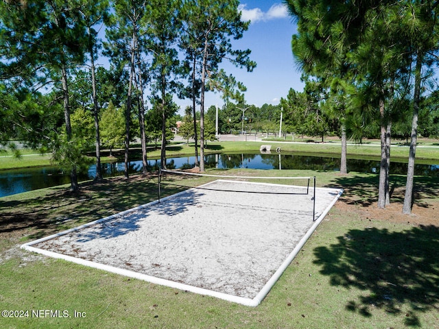 view of property's community with volleyball court, a water view, and a lawn