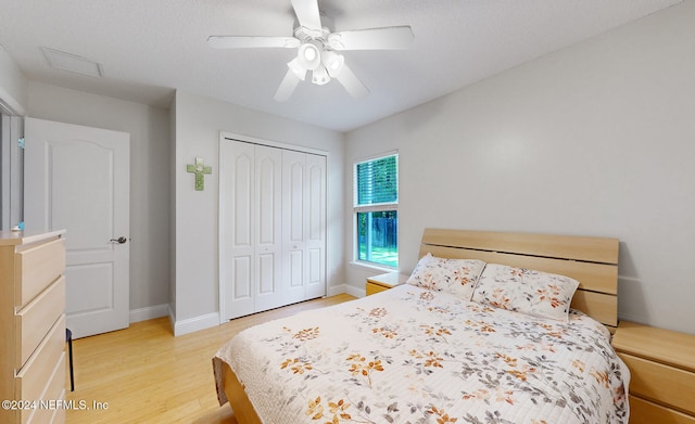 bedroom featuring light hardwood / wood-style floors, ceiling fan, and a closet