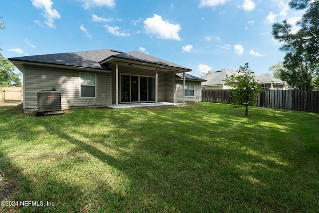 back of house with central air condition unit and a lawn