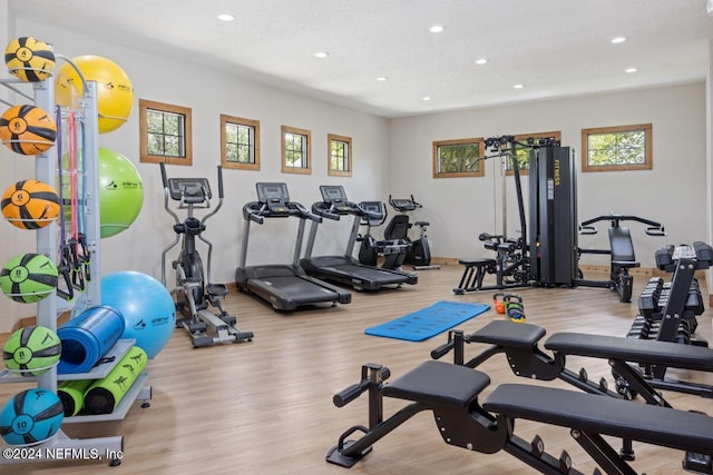 workout area with a textured ceiling and light hardwood / wood-style floors