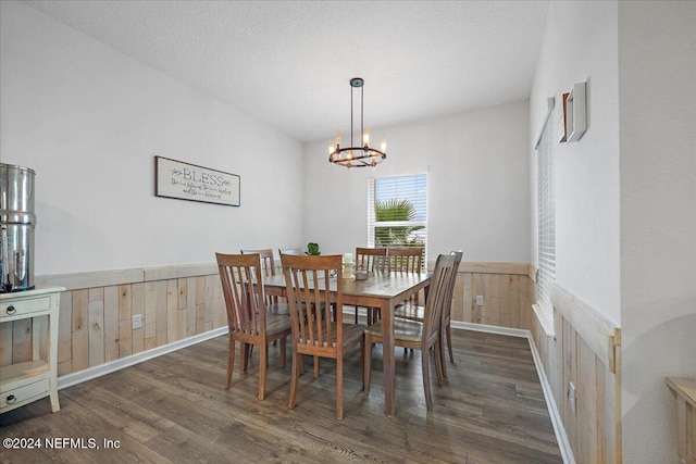 dining room with wooden walls, a textured ceiling, dark hardwood / wood-style floors, and a notable chandelier