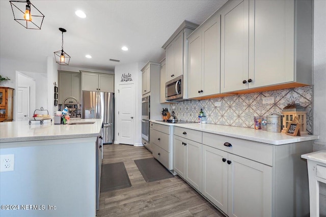 kitchen featuring gray cabinetry, sink, stainless steel appliances, hardwood / wood-style floors, and pendant lighting