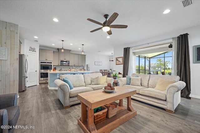 living room with ceiling fan, light hardwood / wood-style flooring, and a textured ceiling