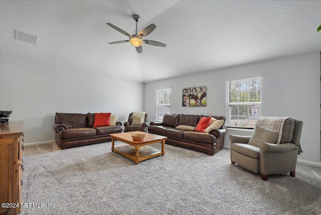 living room featuring vaulted ceiling, ceiling fan, light colored carpet, and a textured ceiling