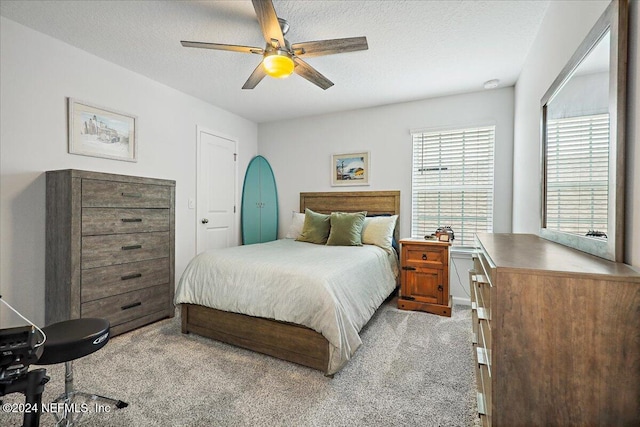 carpeted bedroom featuring ceiling fan and a textured ceiling