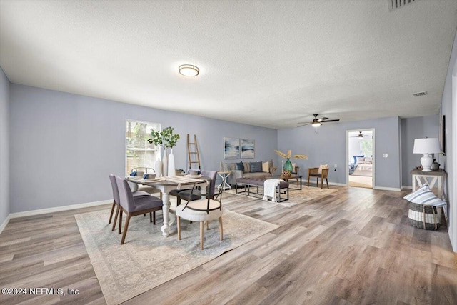 dining area featuring ceiling fan, light hardwood / wood-style floors, and a textured ceiling