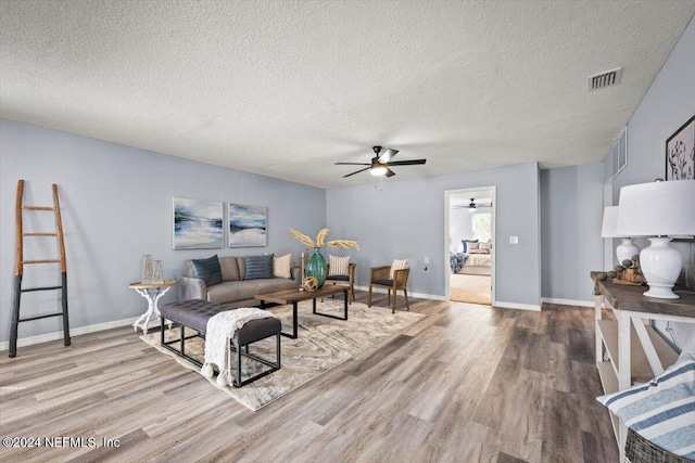 living room with ceiling fan, wood-type flooring, and a textured ceiling