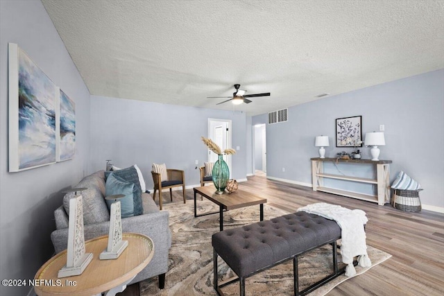 living room with ceiling fan, wood-type flooring, and a textured ceiling