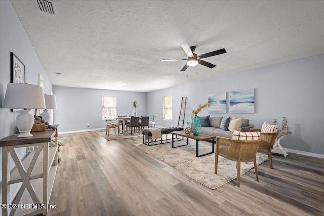 living room with ceiling fan, wood-type flooring, and a textured ceiling