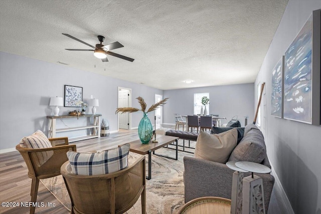 living room with ceiling fan, a textured ceiling, and hardwood / wood-style flooring