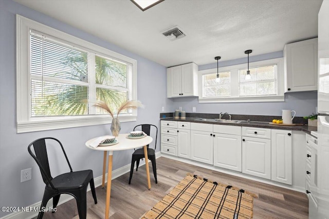 kitchen with light hardwood / wood-style floors, white cabinetry, and sink