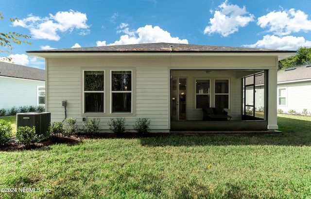 rear view of house featuring a sunroom, a lawn, and central AC