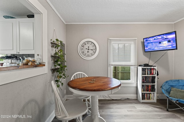 dining room featuring a textured ceiling, light wood-type flooring, and crown molding