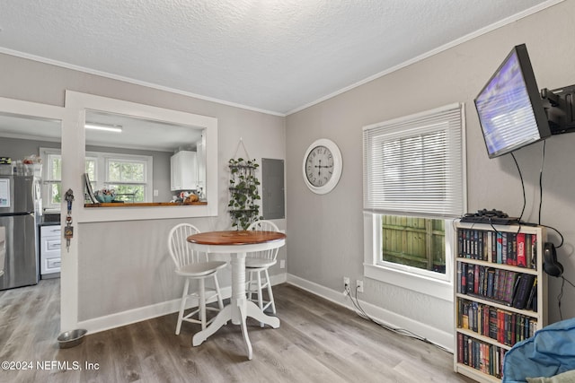 dining space featuring a textured ceiling, light hardwood / wood-style floors, and crown molding