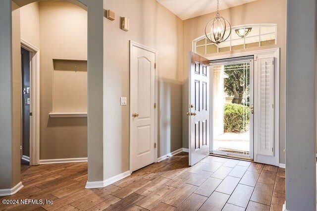 foyer entrance with a high ceiling, hardwood / wood-style floors, and an inviting chandelier