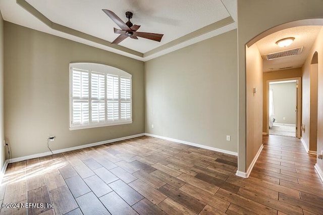 spare room featuring hardwood / wood-style floors, a tray ceiling, and ceiling fan