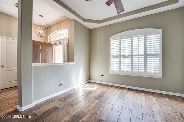 spare room featuring ceiling fan with notable chandelier and plenty of natural light