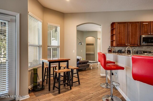 kitchen with light hardwood / wood-style floors, a textured ceiling, and backsplash