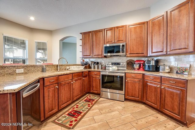 kitchen with light stone countertops, appliances with stainless steel finishes, sink, and backsplash