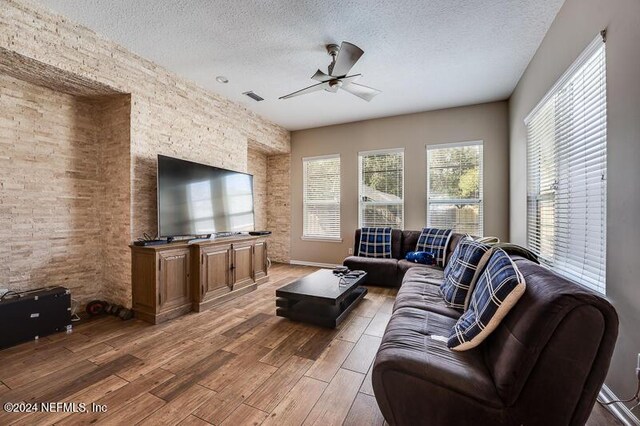 living room featuring ceiling fan, hardwood / wood-style floors, and a textured ceiling