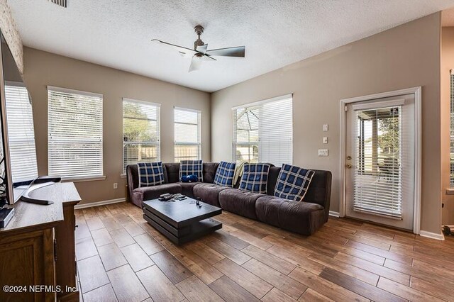 living room with ceiling fan, hardwood / wood-style floors, and a textured ceiling