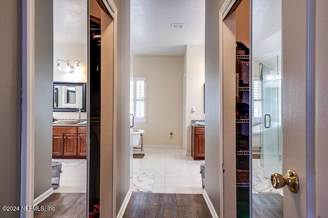 hall with a textured ceiling and light wood-type flooring