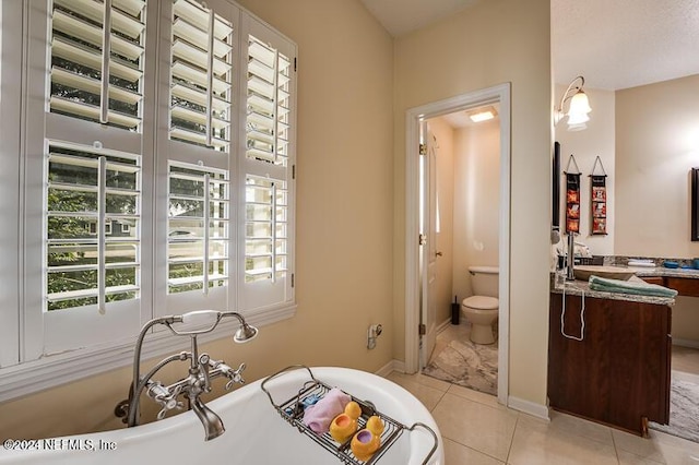 bathroom featuring tile patterned flooring, vanity, a tub to relax in, and toilet