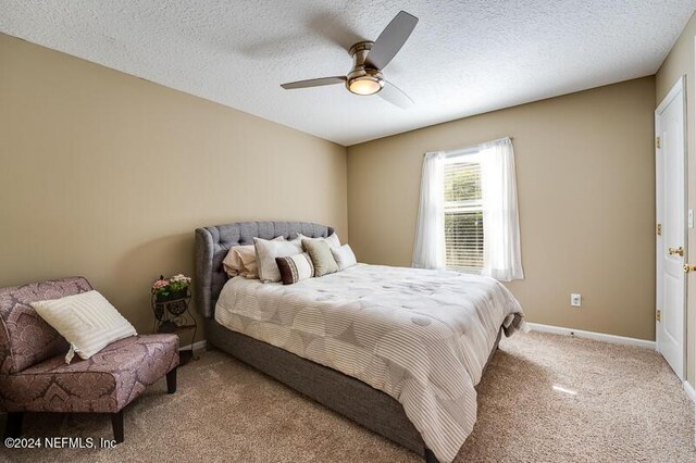 bedroom with ceiling fan, light carpet, and a textured ceiling